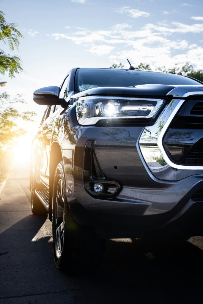 A sleek Toyota Hilux pickup truck with headlights on, captured at sunset showcasing a modern design.