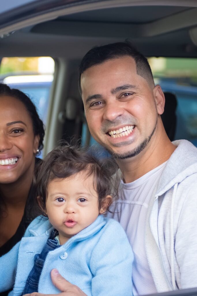 Family of three smiling in a car, showcasing joy and togetherness.