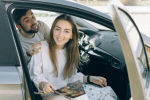 Smiling couple inside a car with map, ready for an adventurous road trip.