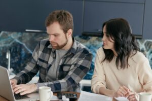 A couple working together on financial planning at home, using a laptop and paperwork.