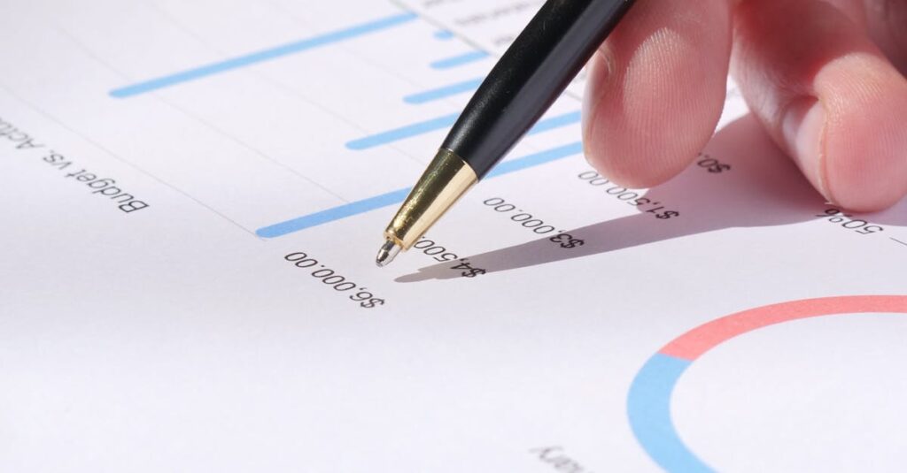 Close-up of hand analyzing data on a monthly budget document with graphs and charts.